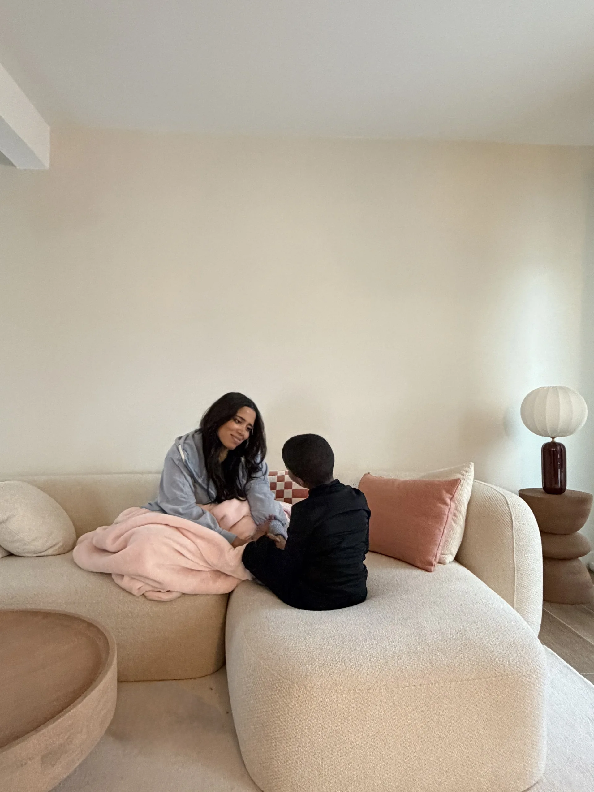 Une mère et son enfant assis face à face sur un canapé beige, en plein dialogue calme et attentif