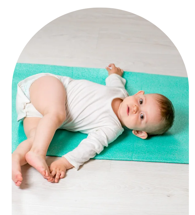 Bébé allongé sur un tapis de yoga vert, dans une posture détendue de Baby Yoga